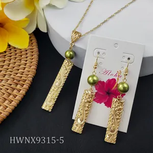 Detail of tropical gold bar earrings and necklace with engraved floral patterns and green pearl