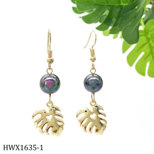 Detail von Gold-Monstera-Ohrringen mit lila Perle und herzförmigem Ausschnitt