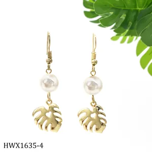 Detailsicht goldener Monstera-Ohrringe mit weißen Perlen und Herz-Ausschnitten