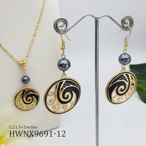 Close-up of gold twist chain necklace and wave earrings with pearls and black enamel