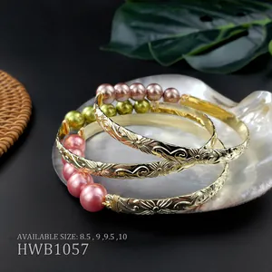 Dettaglio di bracciali in rame incisi con perle naturali colorate in un guscio decorativo