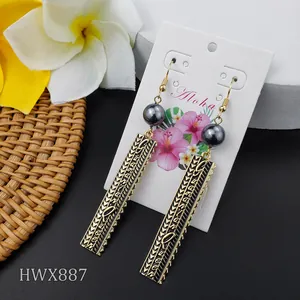 Macro shot of Polynesian tribal earrings with dark grey pearls on Aloha display card