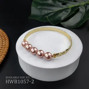 Dettaglio macro del bracciale in rame inciso con perle rosa su base tropicale