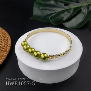 Dettaglio del bracciale rigido in rame dorato con perline verde smeraldo e incisioni vintage
