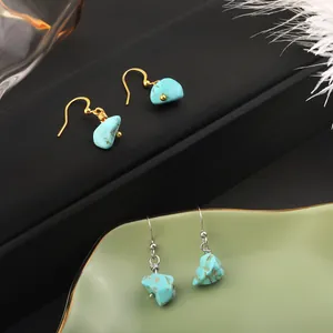 Natural turquoise raw stone drop earrings with gold and silver hooks on ceramic tray