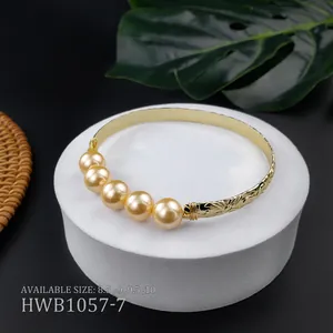 Dettaglio di un bracciale con perle dorate e incisioni floreali su un supporto espositivo