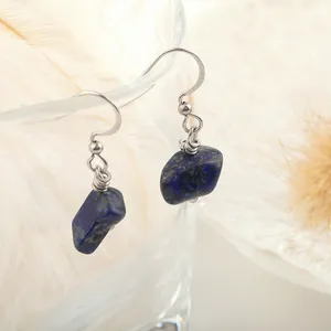 Close-up of natural blue lapis lazuli hook earrings hanging on a glass rim with feathers