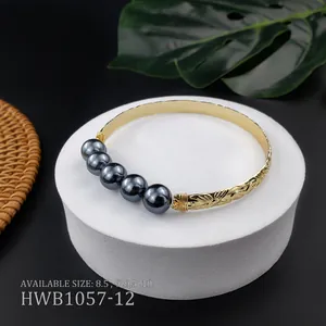 Dettaglio del bracciale hawaiano in rame con perle di conchiglia grigie e incisioni