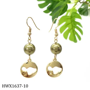 Detailsicht der goldenen Ohrhänger mit grüner Perle und rundem, hohlem geometrischem Anhänger