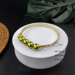 Dettaglio del bracciale dorato largo 6 mm con perle verde oliva e incisioni floreali