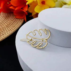 Vue détaillée d'une pince à cheveux feuille de monstera dorée sur un socle géométrique