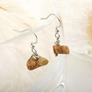 Close-up of natural picture jasper stone earrings with stainless steel hooks on glass