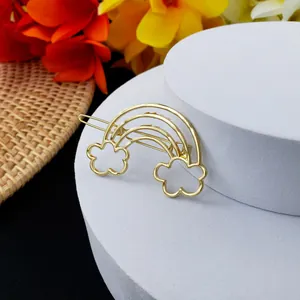Barrette à cheveux dorée en métal avec motif arc-en-ciel et nuage sur socle blanc