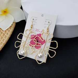 Detail of hollow monstera leaf earrings with white pearls on a tropical Aloha display card