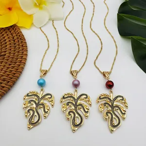 Detail of tropical monstera leaf pendants with colorful beads on gold necklaces