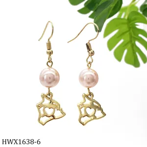 Detailansicht goldener Ohrhänger mit rosa Perlen und hohlen Anhängern in Herzform