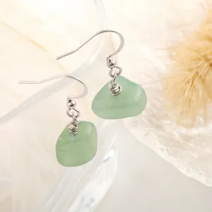 Macro shot of light green natural raw stone earrings with silver stainless steel hooks