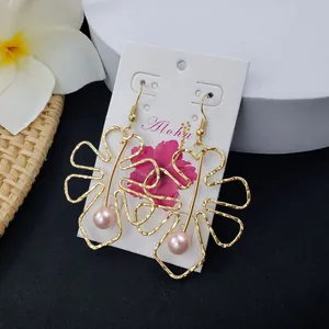 Gold hollow leaf earrings with pink pearl drop on Aloha display card with flowers