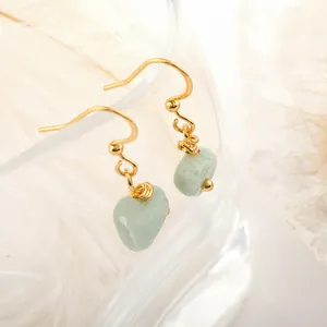 Detail of light green raw natural stone earrings with gold wire-wrapped hooks