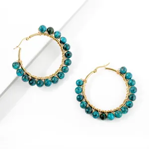 Close-up of bohemian gold wire-wrapped hoop earrings with natural blue stone beads