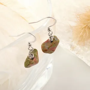 Detail of Unakite stone earrings with silver wire wrapping on a glass rim