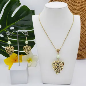Tropical monstera leaf jewelry set with gold necklace and pearl earrings on display