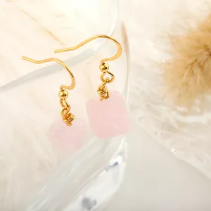 Detail of pink crystal teardrop earrings with gold hooks on a minimalist cream background