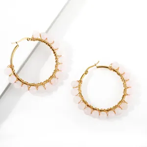Macro shot of handmade gold wire-wrapped hoop earrings with pink crystal beads