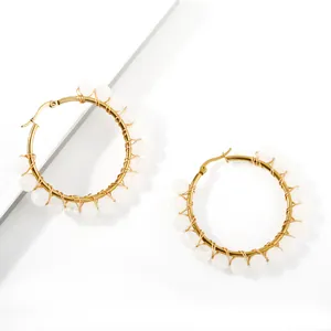 Detail of handmade wire-wrapped gold hoop earrings with white translucent natural stone beads