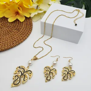 Detail of Monstera leaf jewelry set with gold plating, black enamel, and white pearls