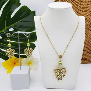 Detail of Monstera leaf pendant set with green faux pearls on white mannequin stand