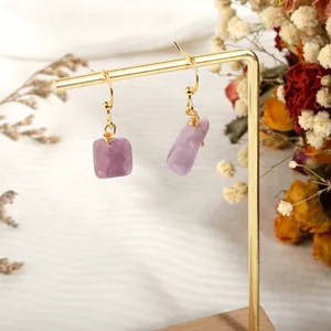 Detail showing asymmetrical lavender natural crystal earrings on a gold metal jewelry stand
