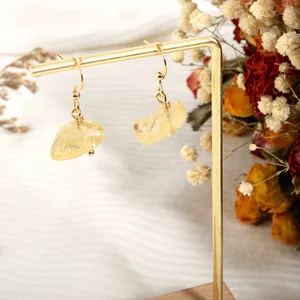 Detail of handmade gold earrings with natural irregular yellow crystal raw stones