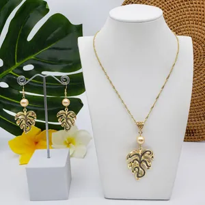 Detail of Monstera leaf jewelry set with gold finish, black texture, and pearls