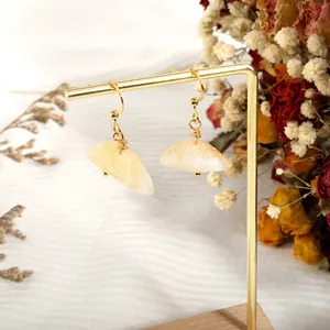 Detail of handmade gold wire-wrapped earrings with irregular raw yellow quartz stones