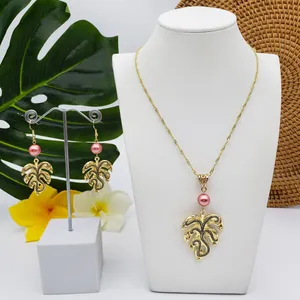 Macro shot of tropical golden Monstera leaf necklace and earrings with pink pearls