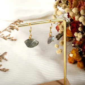 Detail of natural grey crystal earrings with gold wire wrap on a jewelry display stand