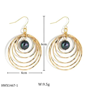 Detail view of gold layered hoop earrings with natural mother-of-pearl black bead drop