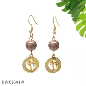 Detailaufnahme goldener Hawaii-Ohrringe mit Palmenrelief und einer braunen Perle