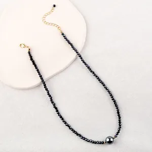 Minimalist black faceted bead necklace with a large grey pearl and golden clasp
