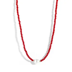 Detail of red faceted crystal beads necklace with a single white pearl and gold spacers