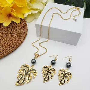 Detail of Monstera leaf jewelry set with dark pearls and tropical gold leaf design
