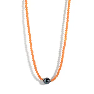 Macro view of faceted orange beads and dark central pearl on a minimalist choker