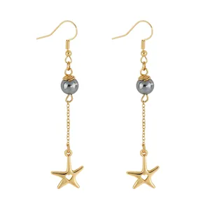 Detail of gold star pendant with heart cutout and dark grey pearl on dangle earrings