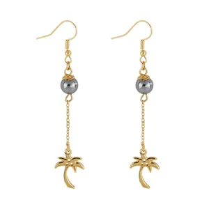 Golden palm tree dangle earrings with dark grey beads on white background
