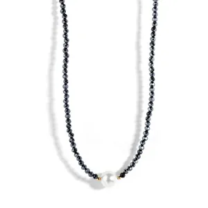 Detailed view of faceted black beaded choker with a central white shell pearl and gold accents