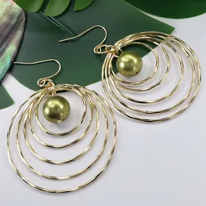 Detail of bohemian gold hollow circular earrings with green mother of pearl beads