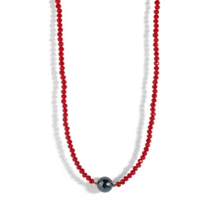 Detail of red faceted glass beads necklace with a dark iridescent pearl centerpiece