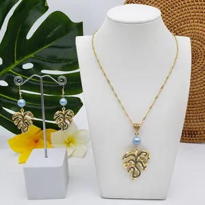Macro detail of gold Monstera leaf jewelry set featuring blue pearl beads on display
