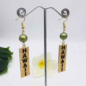 Detail of gold Hawaiian earrings featuring olive beads and engraved Hawaii text